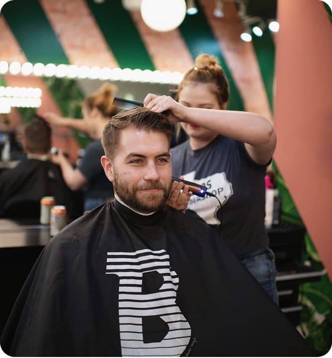 A barber cutting a client's hair at Bird's Barbershop in Austin